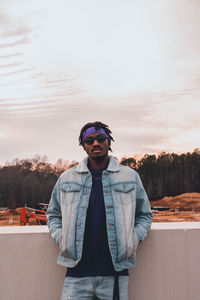 Portrait of young man standing against sky