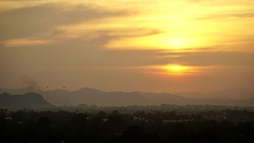 Scenic view of silhouette mountains against orange sky