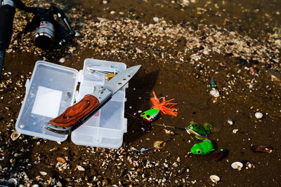 Fishing hooks with box and knife on sand