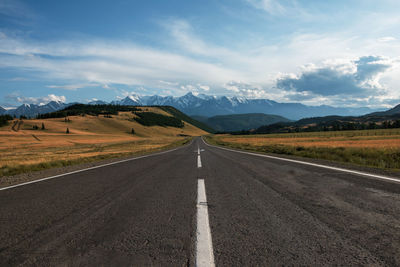 Road leading towards mountains against sky