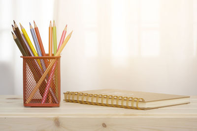 Close-up of pencils in organizer by spiral notebook on desk