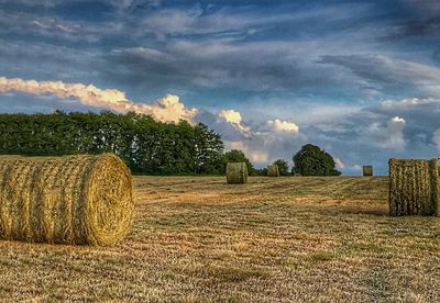 Hay bales on field against sky