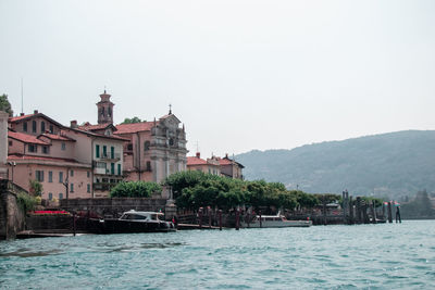 Buildings by sea against clear sky