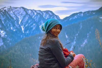 Woman wearing hat against mountains during winter