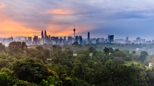 Trees and buildings against sky during sunset