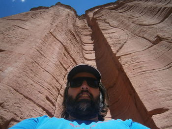 Low angle portrait of man wearing sunglasses by rock formations