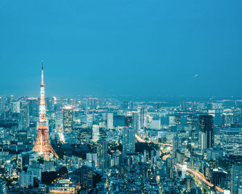 Illuminated cityscape against clear blue sky