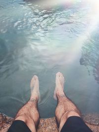 Low section of man relaxing by lake