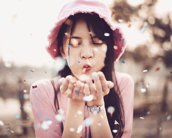 Young woman wearing hat blowing confetti