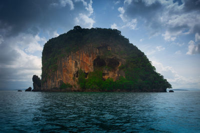 Rock formation by sea against sky