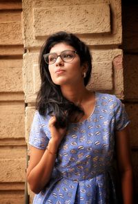 Beautiful young woman standing against wall