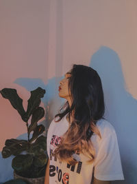 Portrait of young woman standing against wall