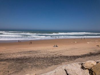 Scenic view of beach against clear blue sky