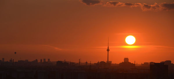 Silhouette of buildings against cloudy sky during sunset