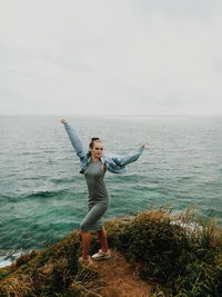 Full length of woman standing by sea against sky