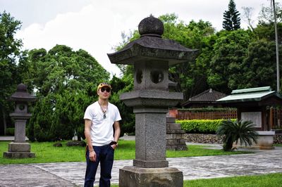 Young man standing by stone lantern at garden