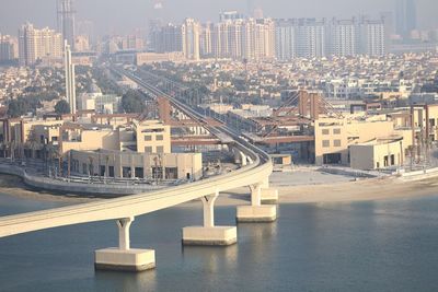 Bridge over river amidst buildings in city against sky