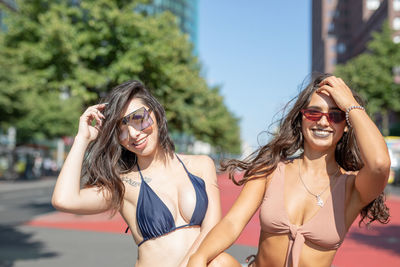 Portrait of fashionable young women wearing bikinis in city