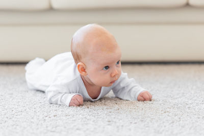 Cute baby boy sitting on floor at home