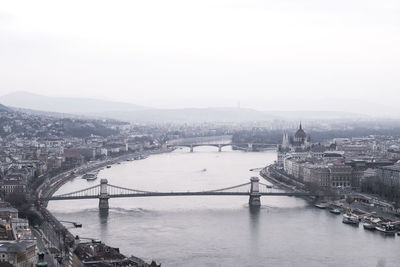 Chain bridge over river danube amidst city against sky