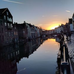 Canal amidst buildings against sky at sunset
