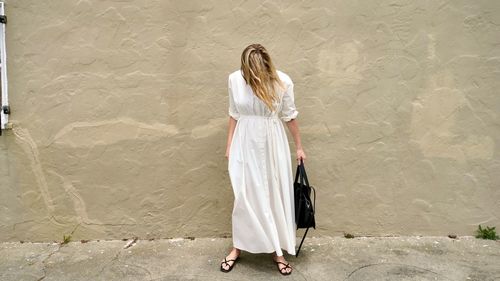 Woman with umbrella standing against wall