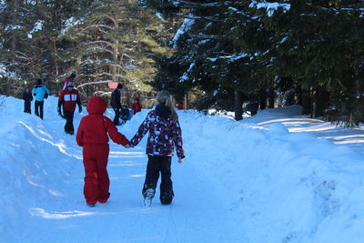 People walking on snow covered christmas tree during winter