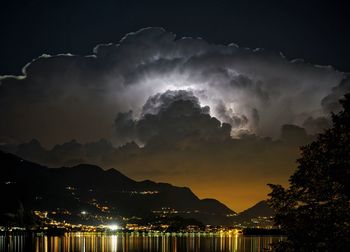 Illuminated town at night with dramatic sky