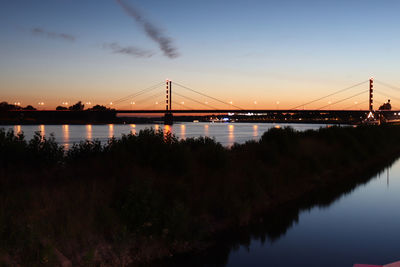 View of suspension bridge over river during sunset