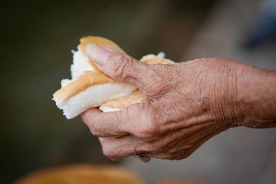 Close-up of man holding bread outdoors