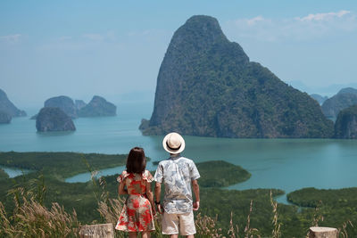 Rear view of woman looking at sea against mountain