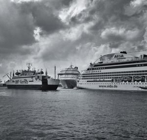 Boats in river against cloudy sky