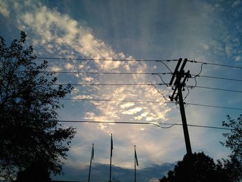 Low angle view of electricity pylon against cloudy sky