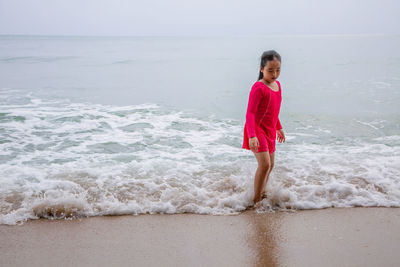 Girl standing on beach against sea