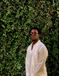 Portrait of young man standing against plants