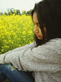 Side view of sad woman sitting by field