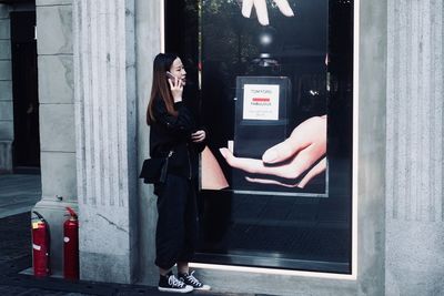 Woman photographing with mobile phone while standing on laptop