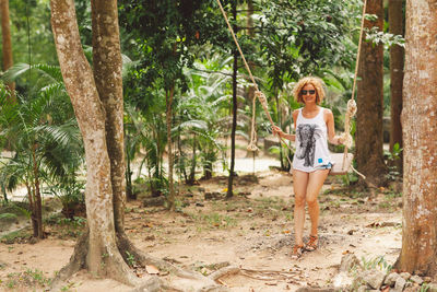 Full length portrait of smiling woman siting on swing in park