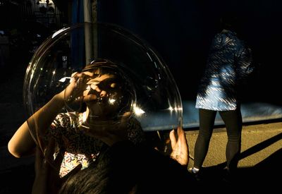 Child blowing bubble on footpath at night