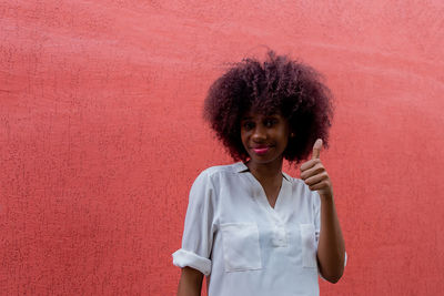 Portrait of woman standing against red wall