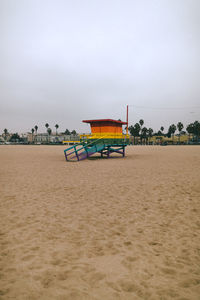 Deck chairs on beach against sky