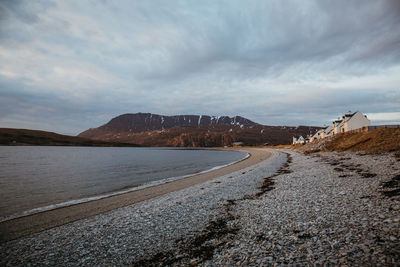 Scenic view of lakeshore against cloudy sky