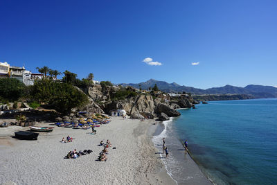 People on beach against blue sky