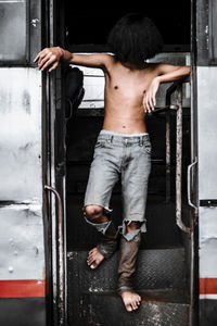 Rear view of shirtless man standing by door