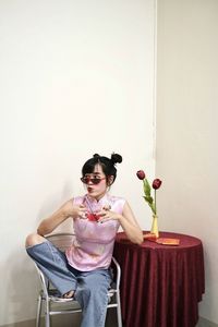 Portrait of woman in pink cheongsam top and jeans holding a cup of red water