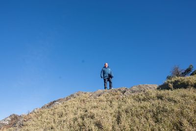 Man standing on field against clear blue sky