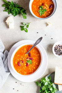 A bowl of homemade red bean and lentil soup, bread and parsley. vegetable spicy soup. 