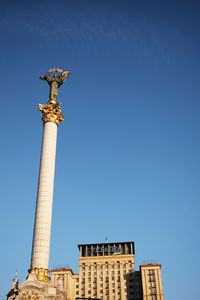 Low angle view of statue of historic building against blue sky