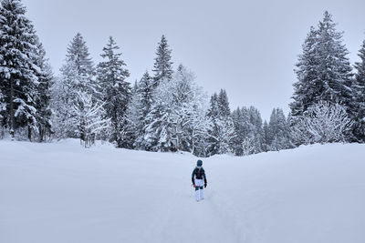 Rear view of woman on snow covered land against sky