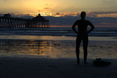 Silhouette man standing at beach during sunset